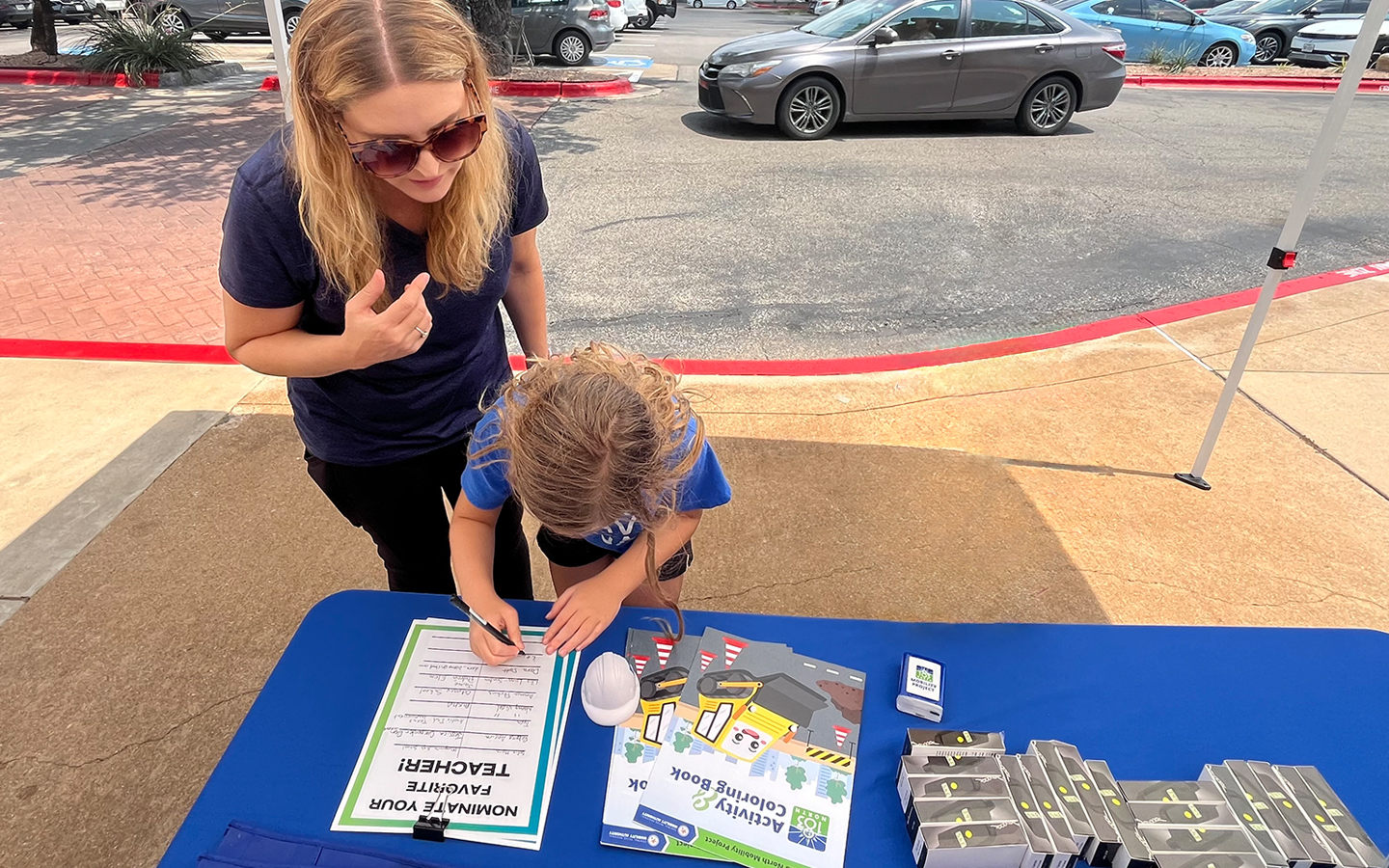 Woman and child standing at a table writing on a sign up sheet