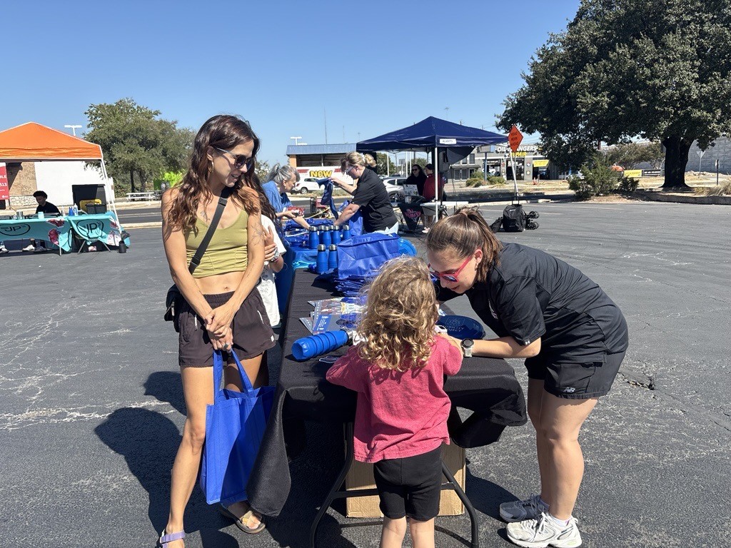 woman and child greet project representative at promotional items table