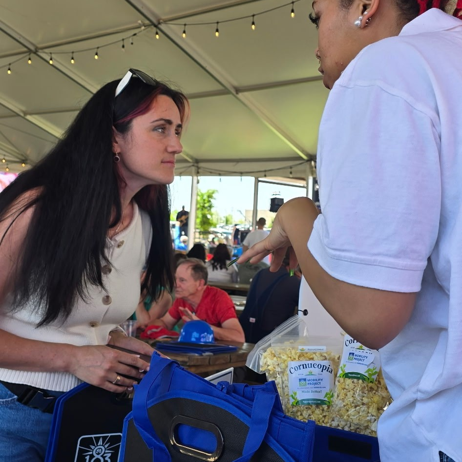 Two women speak over an informational table with giveaway items